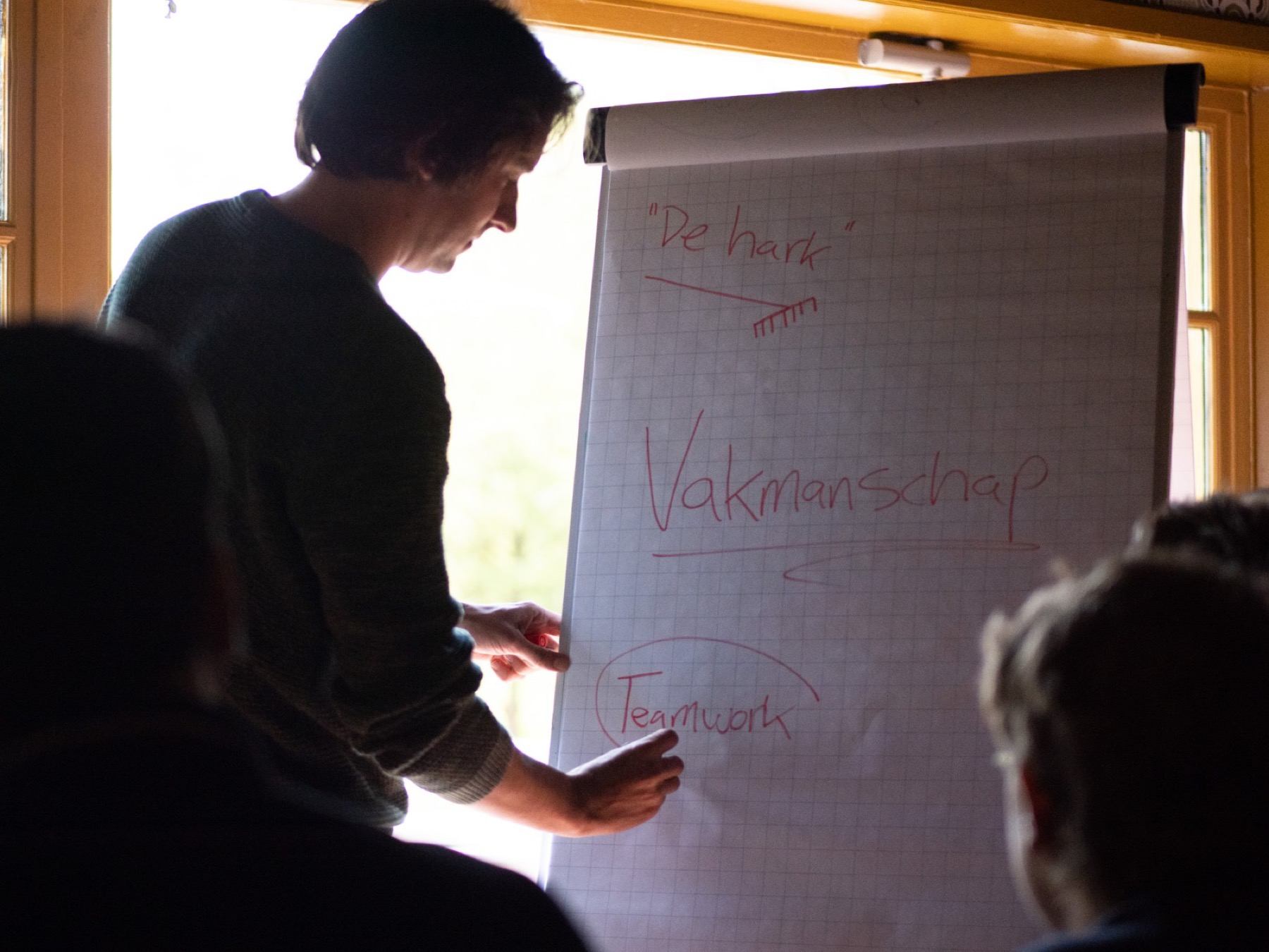 Flipchart met de handgeschreven woorden vakmanschap en teamwork, tijdens een kernwaardensessie.