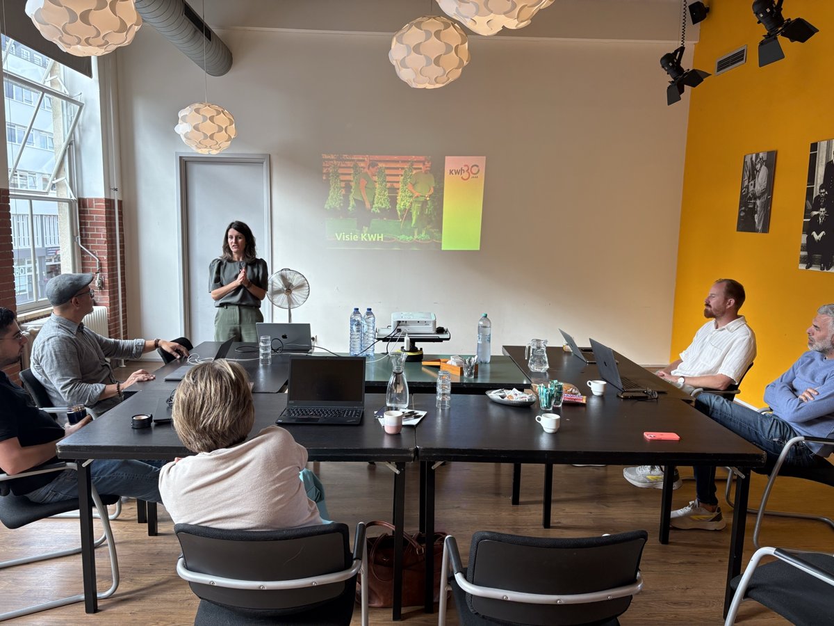 Een presentatie aan tafel tijdens een sessie, de deelnemers kijken mee op het scherm.